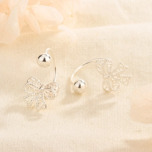 Macro shot of silver lace bow earrings with delicate hollow filigree and screw backs