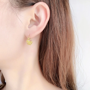 Close-up of golden hollow lace bow earring with frosted finish on female model