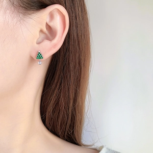 Detail of Christmas tree stud earring with green zircons worn on a model ear