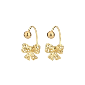 Close-up of golden hollow lace bow earrings with intricate vintage woven textures
