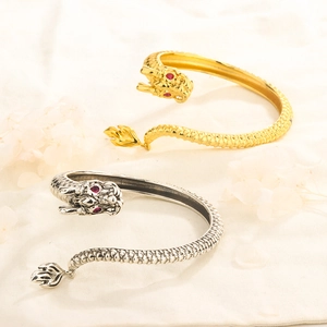 Detailed dragon-shaped open bracelets in 14K gold and silver with red gemstone eyes