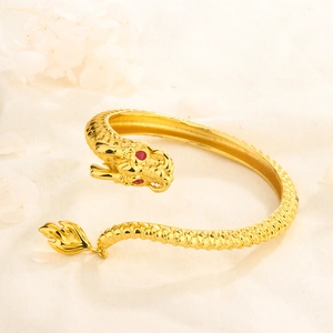Detailed macro view of 14K gold dragon bracelet with red gemstone eyes and scales