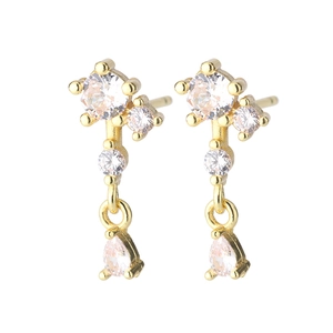 Détail de boucles d'oreilles pendantes dorées avec zircons ronds et en forme de goutte