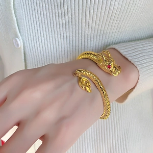 Detail of 14K gold-plated dragon bracelet with red gem eyes and scaly texture