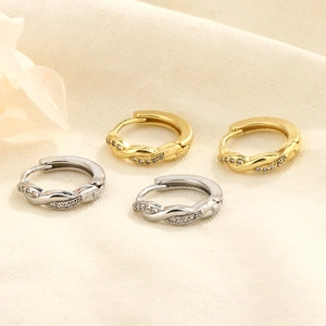Détail de boucles d'oreilles créoles Mobius torsadées en or et argent avec cristaux brillants