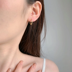 Close-up of minimalist gold huggie hoop earrings worn by a model in a side view