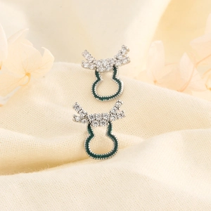 Macro view of elk antler and green enamel gourd earrings with cubic zirconia