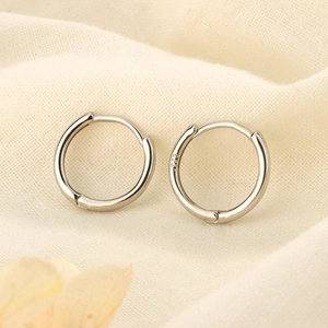 Detailed close-up of polished S925 sterling silver hoop earrings on soft fabric