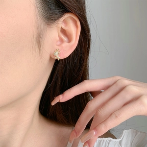 Close-up of a golden reindeer stud earring with diamonds worn on a woman ear