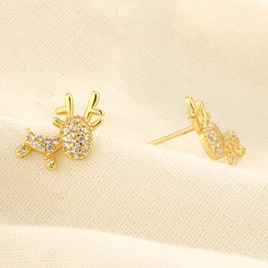 Close-up of gold reindeer earrings with sparkling zircon crystals on white fabric