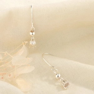 Detailed close-up of S925 silver lily of the valley earrings on textured fabric