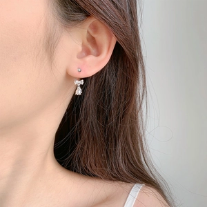 Boucles d'oreilles nœud muguet argentées avec pompon portées avec élégance