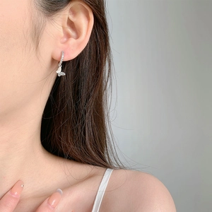 Boucles d'oreilles créoles papillon en argent portées par un mannequin sur fond gris