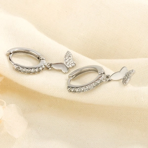 Boucles d'oreilles créoles papillon en argent avec zircons blancs sur fond en lin fin