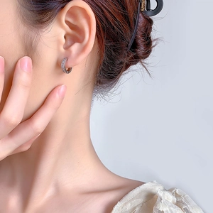 Close-up of a silver paved rhinestone hoop earring worn on an ear for a daily look