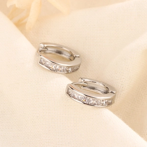 Elegant silver hoop earrings with square-cut cubic zirconia on beige fabric
