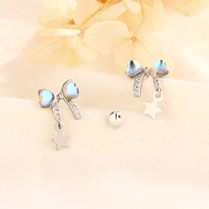 Macro shot of silver bow earrings with blue opal heart stones and star charms