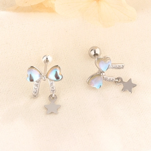 Elegant bow stud earrings with iridescent heart wings and star charms on beige fabric