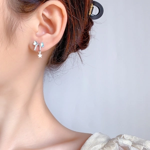 Elegant bow stud earrings with iridescent gemstone and small star pendant on model