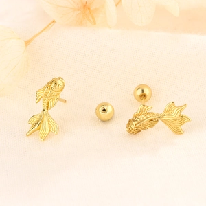 Détail macro de boucles d'oreilles carpe koï dorées avec texture fine et écailles en métal