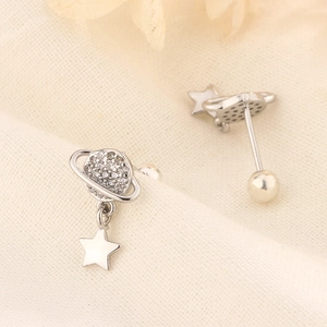 Macro detail of silver Saturn earrings with cubic zirconia and star charm