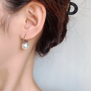 Close-up of minimalist white pearl drop earrings with elegant silver metal hooks