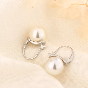 Elegant white pearl drop earrings with silver leverback hooks on soft textured linen