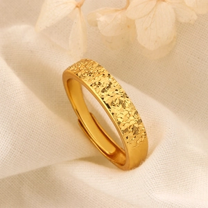Détail d'une bague dorée réglable avec surface martelée texturée sur tissu blanc