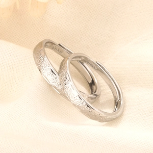 Close-up of S925 sterling silver couple rings with unique hammered texture on white fabric