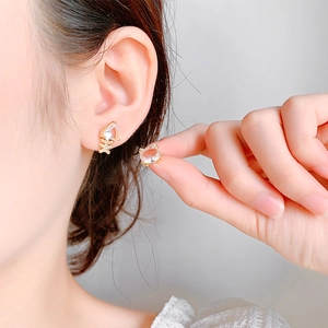 Gros plan de boucles d'oreilles asymétriques chat et arête avec cristaux sur l'oreille