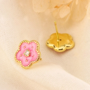 Macro detail of peach blossom enamel earrings with pink petals and gold metal finish