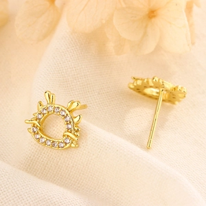 Detailed close-up of golden dragon earrings with cubic zirconia on textured fabric