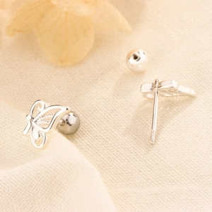 Elegant hollow butterfly screw back earrings in silver metal on beige fabric