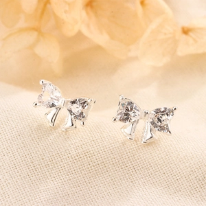 Detailed macro view of S925 silver bow stud earrings featuring heart-cut cubic zirconia