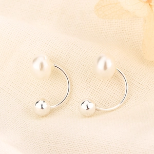 Macro shot of U-shaped silver earrings with polished white pearls and silver metal beads