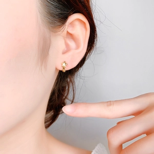 Minimalist gold star-shaped hoop earrings with a polished finish worn on ear