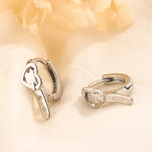 Polished silver heart belt buckle hoop earrings on a warm textured fabric backdrop