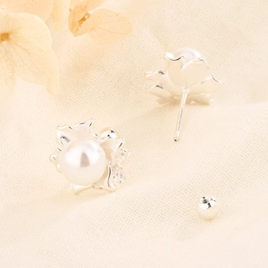 Silver flower pearl stud earrings with screw back design on a textured fabric background