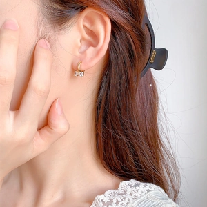 Gros plan d'une boucle d'oreille nœud plaquée or avec zircons transparents sur un mannequin