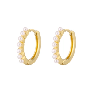 Macro detail of gold-plated huggie hoop earrings featuring seven small white pearls