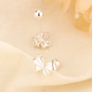 Detailed close-up of polished silver bow stud earrings with secure screw-back ball closures