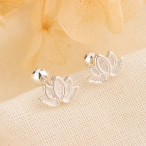 Macro shot of silver lotus screw-back earrings with frosted petals on textured fabric