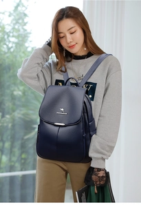 Close-up of dark blue pebble leather backpack featuring a kangaroo logo and flap design