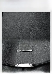 Detail of black lychee grain leather backpack with silver kangaroo logo and hardware