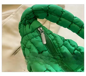 Detail of the smooth silver metal zipper on a bright green quilted puffer tote bag