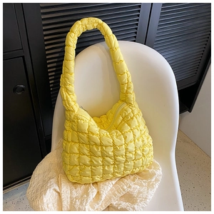 Detail shot of bright yellow quilted cloud tote bag with puffy texture on a white chair