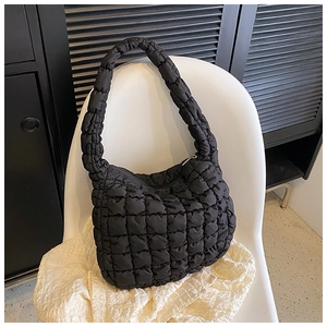 Detailed view of black quilted tote bag showing soft nylon texture on a white chair