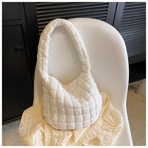 Detail of white quilted cloud bag with padded diamond stitching and metallic zipper