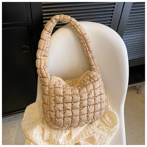 Detail of khaki quilted shoulder bag showing the textured puffy square patterns and zipper