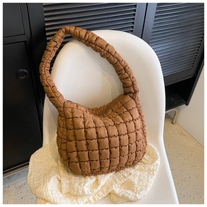 Detail of brown quilted puffer shoulder bag showing soft padded texture on a chair